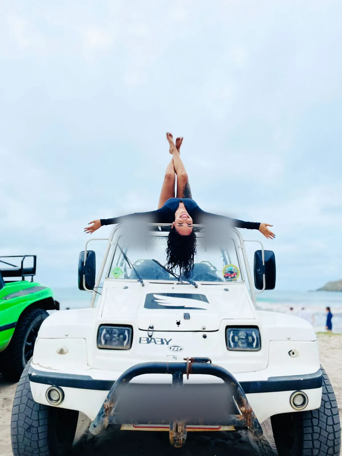 Passageira posando sobre o capô do buggy na beira da praia