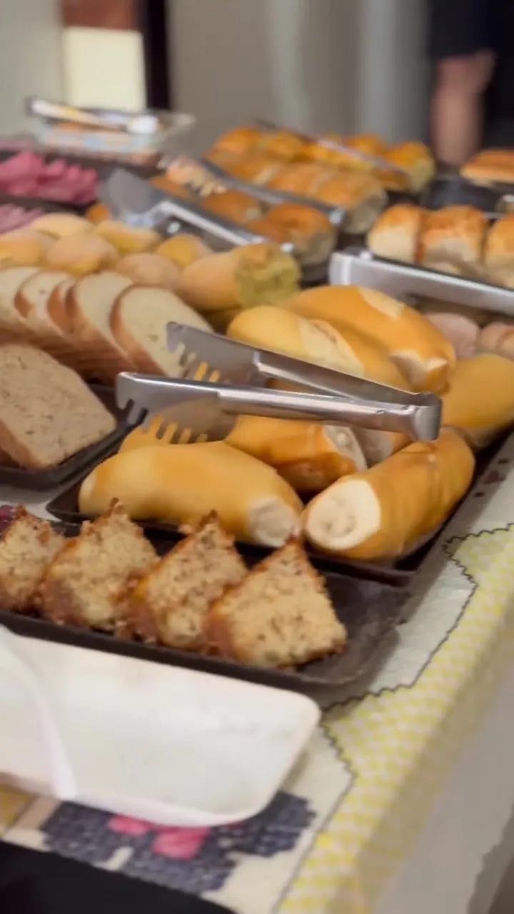 Mesa do café da manhã da pousada com pães, bolos e frios