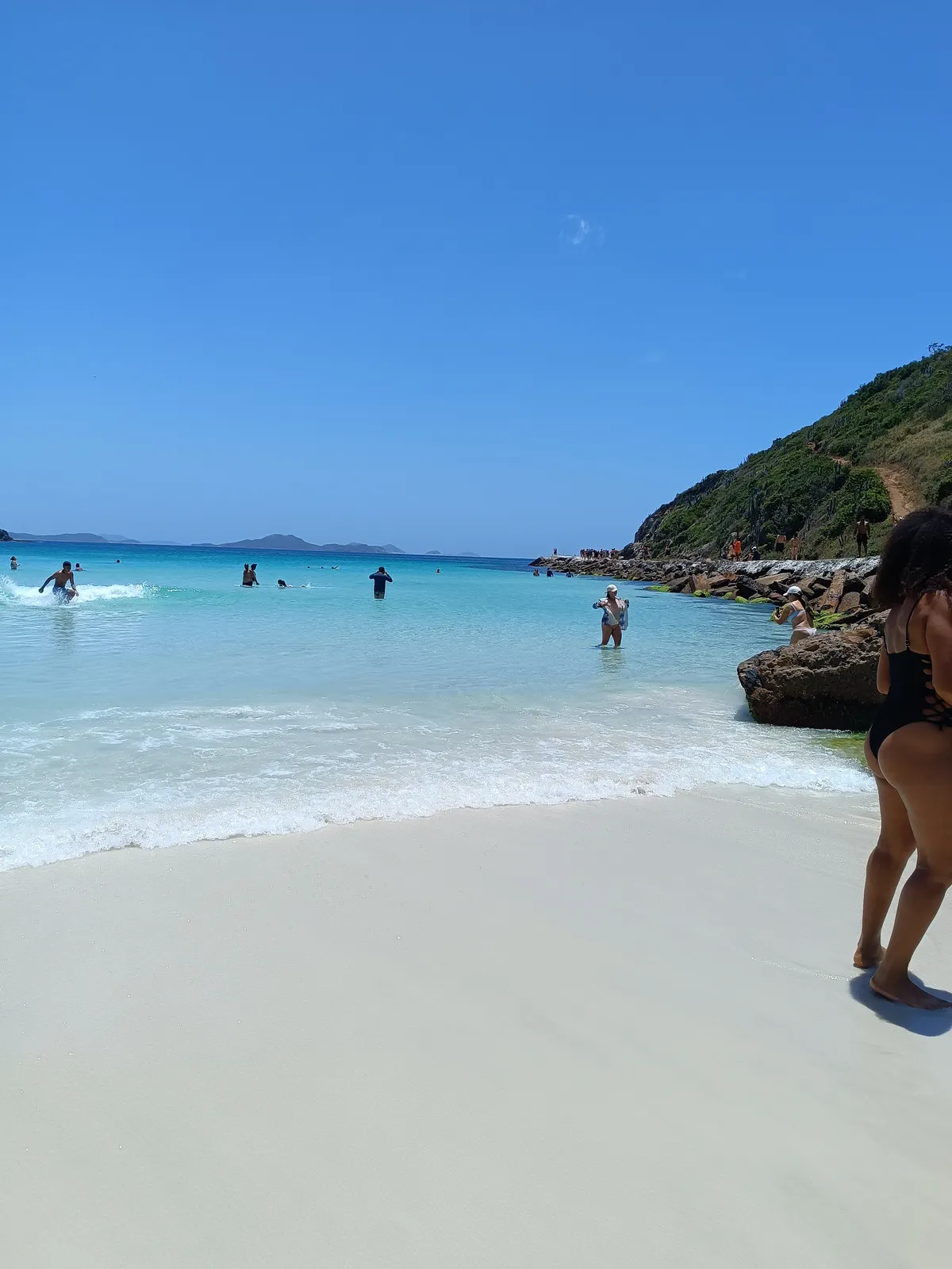 Praia de Arraial do Cabo com costão verde e água turquesa